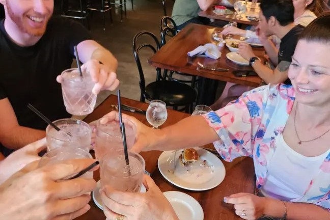 Group of people at a restaurant table toasting with drinks.