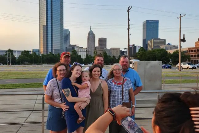Group of people posing for a photo with city skyscrapers in the background.