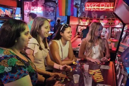 Four people playing arcade games in a colorful room.