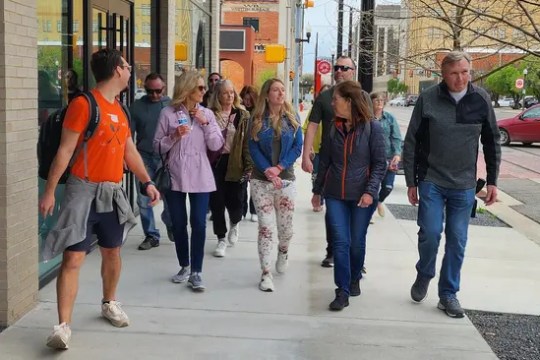 Group of people walking on a city sidewalk on a sunny day.