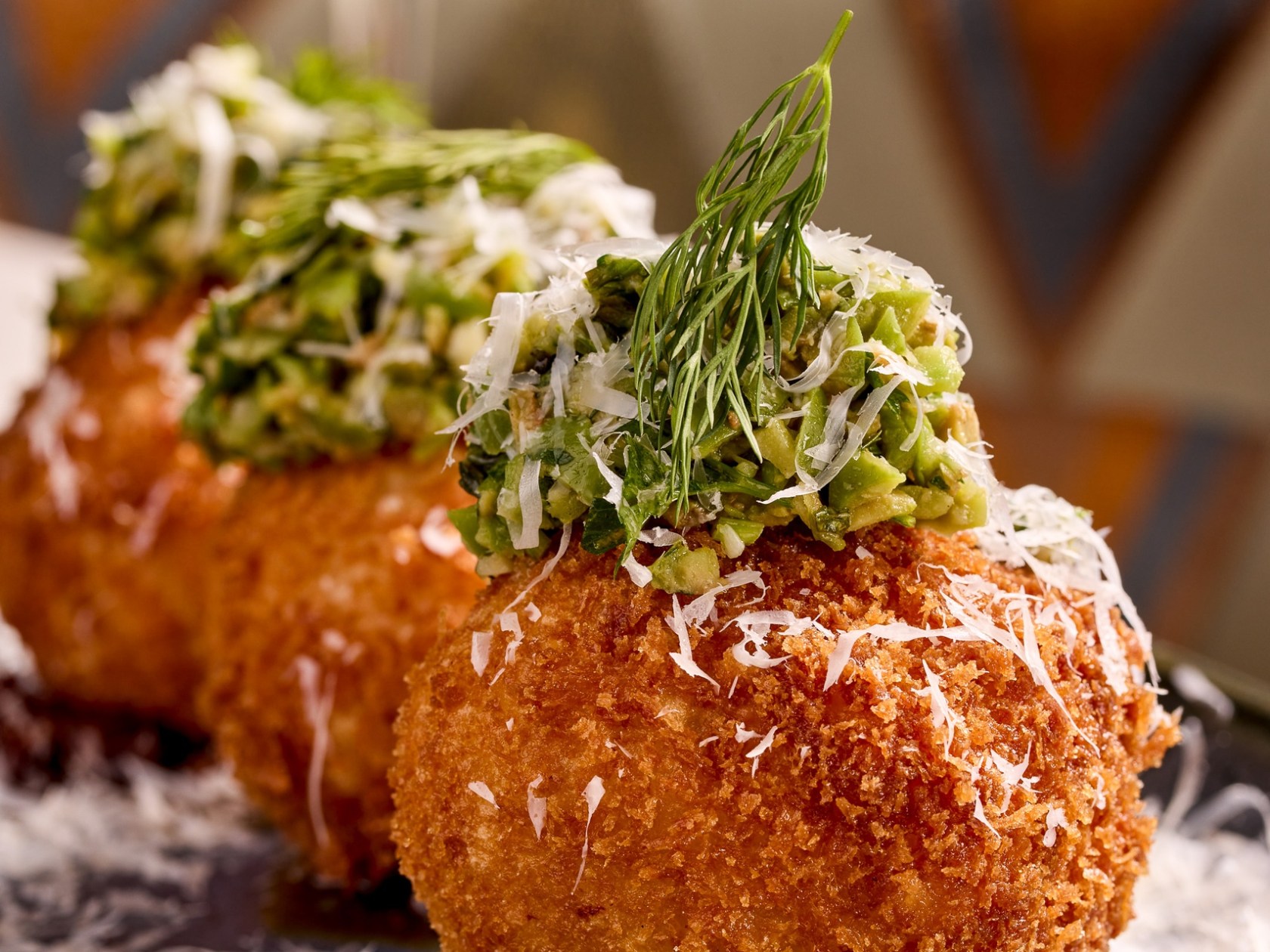 Three arancini balls garnished with herbs on a plate.